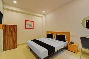 A hotel room with a bed, bedside table, a mirror, a wooden wardrobe, and a framed picture on the wall. - Super Collection O ECIL Crossway (Hyderabad)