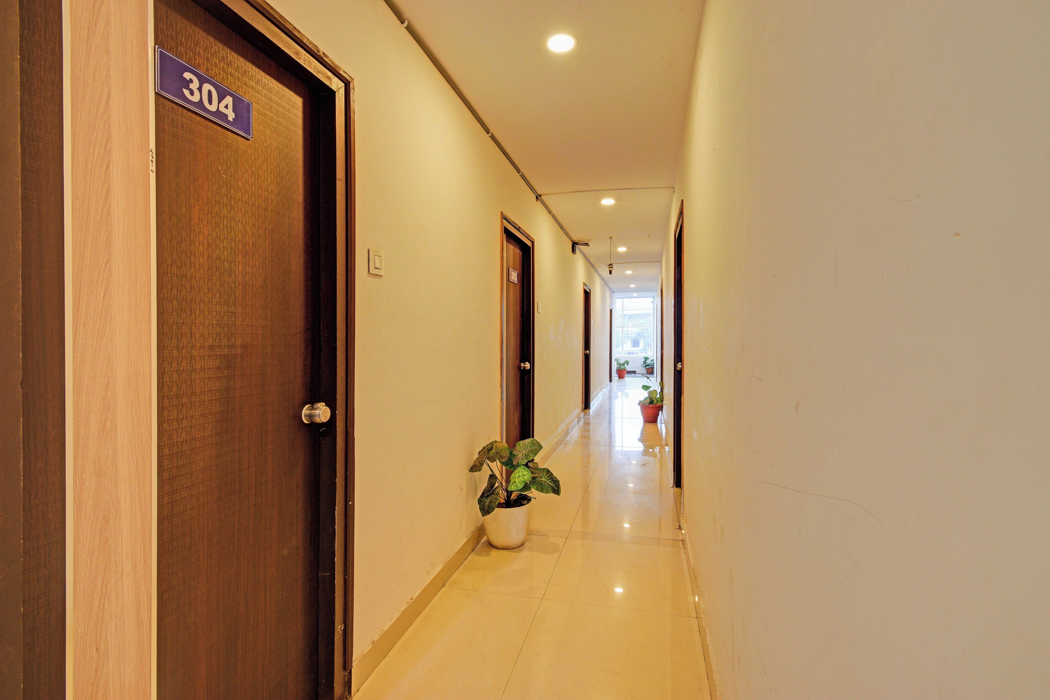 Un pasillo de hotel con una puerta de madera con la etiqueta '304' y una planta en maceta.