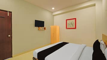 Una habitación de hotel con una cama, un armario, un televisor montado en la pared y un cuadro enmarcado.