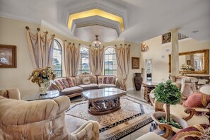 Ein luxuriöses Wohnzimmer mit einer großzügigen Eckcouch, einem Glastisch und aufwendiger Dekoration.