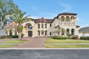 A two-story house with a tiled roof, arched windows, and a front porch. - Lakefront Infinity Pool | Theater | Star Wars 2713 (Kissimmee)