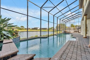 An indoor swimming pool with a view of a lake and buildings in the background. - Lakefront Infinity Pool | Theater | Star Wars 2713 (Kissimmee)