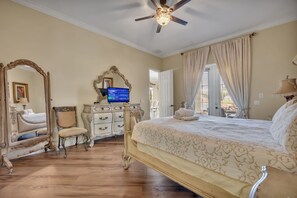A bedroom with a large bed, a vanity with a mirror, a television, and a ceiling fan. - Lakefront Infinity Pool | Theater | Star Wars 2713 (Kissimmee)