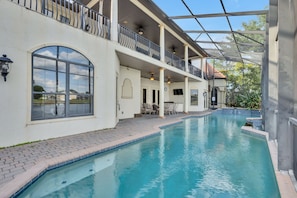 Ein Schwimmbad mit überdachter Terrasse, einem großen Rundbogenfenster und einem Balkon mit Geländern.