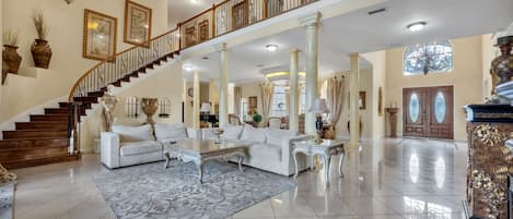 A spacious living area with a grand staircase, elegant furniture, and decorative elements.