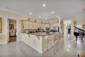 A spacious kitchen with a central island, stainless steel appliances, and a piano in the adjacent room. - Lakefront Infinity Pool | Theater | Star Wars 2713 (Kissimmee)