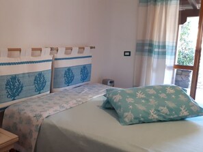 A bedroom with a bed, a nightstand, a lamp, and a window with curtains. - Holiday Home in Olbia With Swimming Pool (Olbia)