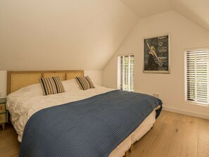 A bedroom with a large bed, a headboard, a window with blinds, and a poster on the wall. - Holiday Home in Renesse With Swimming Pool (Renesse)