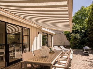 An outdoor patio with a wooden table, chairs, and a large umbrella. - Holiday Home in Renesse With Swimming Pool (Renesse)