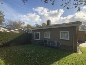 A residential building with a brick exterior, a chimney, and a small front yard with a hedge and a bench. - Wielewaal Side Wing (Cadzand-Bad)