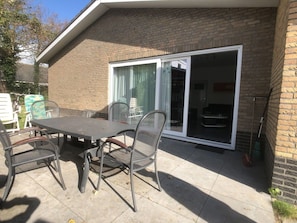 A patio with a table and chairs, a sliding glass door, and a brick wall. - Wielewaal Side Wing (Cadzand-Bad)
