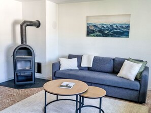 A living room with a gray sofa, two round tables, a book, a fireplace, and a painting on the wall. - Dein Bergmoment by Interhome (Wildhaus)