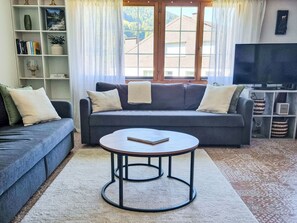 A living room with a sofa, a coffee table, and a television. - Dein Bergmoment by Interhome (Wildhaus)