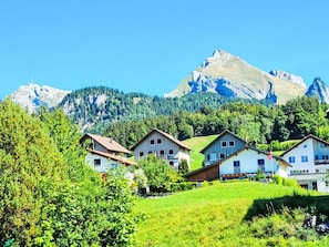 A mountain village with traditional houses, a clear sky, and a prominent mountain peak in the background. - Dein Bergmoment by Interhome (Wildhaus)
