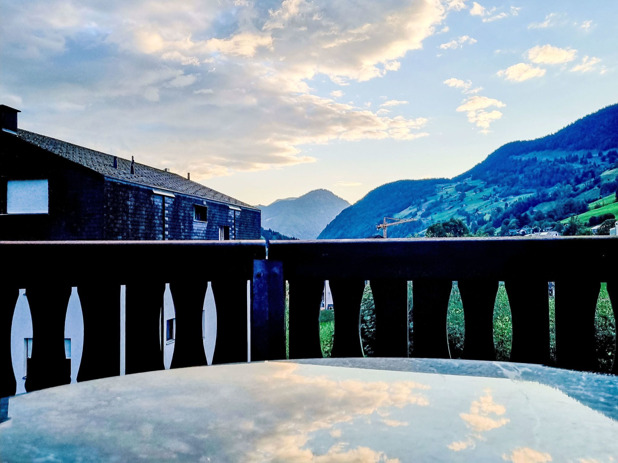 Un balcon donnant sur un paysage montagneux et un bâtiment doté d’un toit en pente.