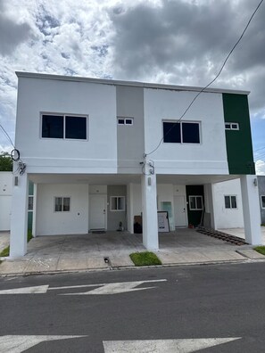 A two-story building with a flat roof, white and green exterior walls, and a covered entrance area.