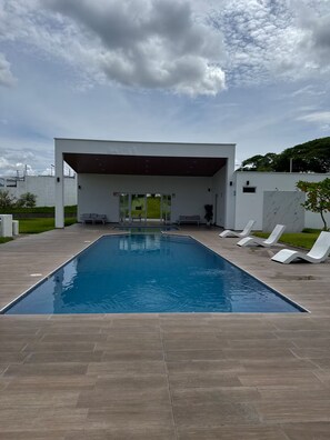 A modern outdoor pool area with a covered seating area and lounge chairs. - Twin Paradise Villas II (Hato Nuevo)