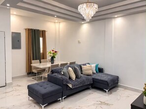 A modern living room with a sectional sofa, a dining table, and a chandelier. - Twin Paradise Villas II (Hato Nuevo)