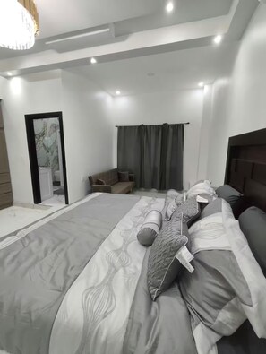 Ein modernes Schlafzimmer mit einem großen Bett, einer Couch und einem Kopfteil.