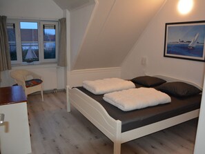 Ein Einzelbett mit weißer Bettwäsche in einem Zimmer mit geneigter Decke.