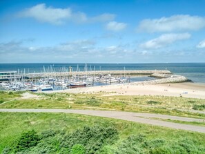 Ein Yachthafen mit zahlreichen Booten, ein Sandstrand und ein klarer Himmel.