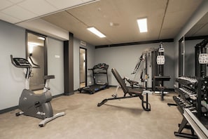 A gym with cardio equipment, weight machines, and dumbbells.