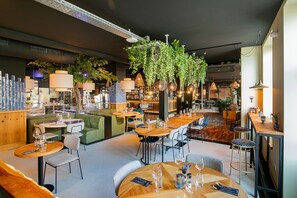 A restaurant interior with multiple dining tables and chairs, hanging plants, and pendant lighting. - City Break & Fluwel's Tulpenland 6.7 mi (Schagen)