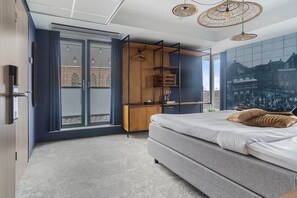 A modern bedroom with a large bed, a wardrobe, and a view of a cityscape through the window. - City Break & Fluwel's Tulpenland 6.7 mi (Schagen)