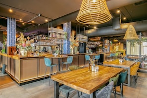 Un espace bar moderne, doté de mobilier en bois, d’un comptoir et d’une variété de bouteilles et de verres.