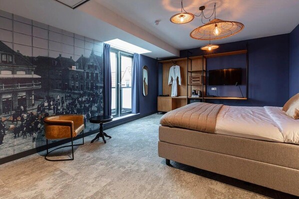 A modern bedroom with a large bed, a cityscape mural, a television, and a seating area with a chair and table. - City Break & Fluwel's Tulpenland 6.7 mi (Schagen)
