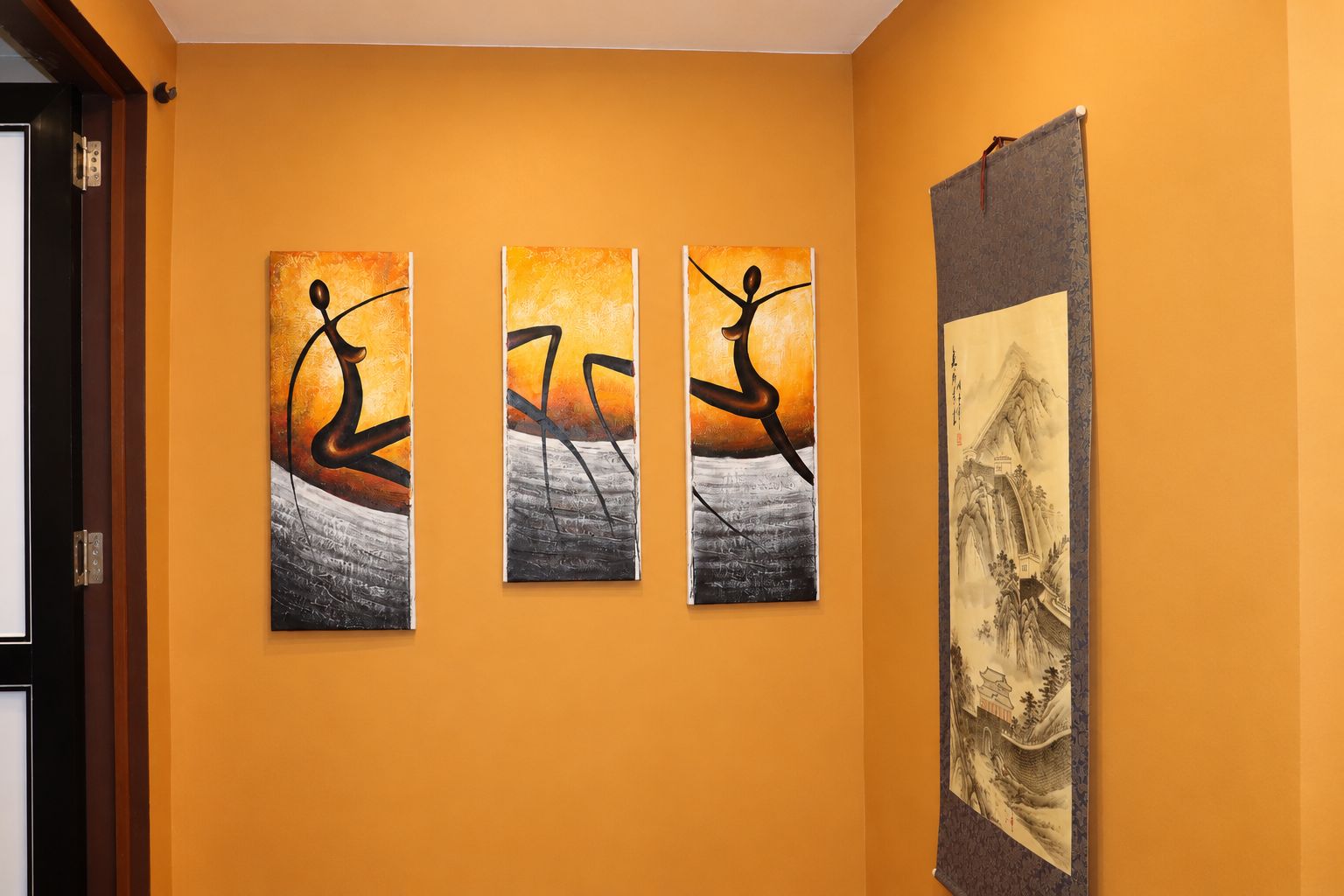 A hallway with three abstract paintings on the wall and a traditional landscape painting on the right.