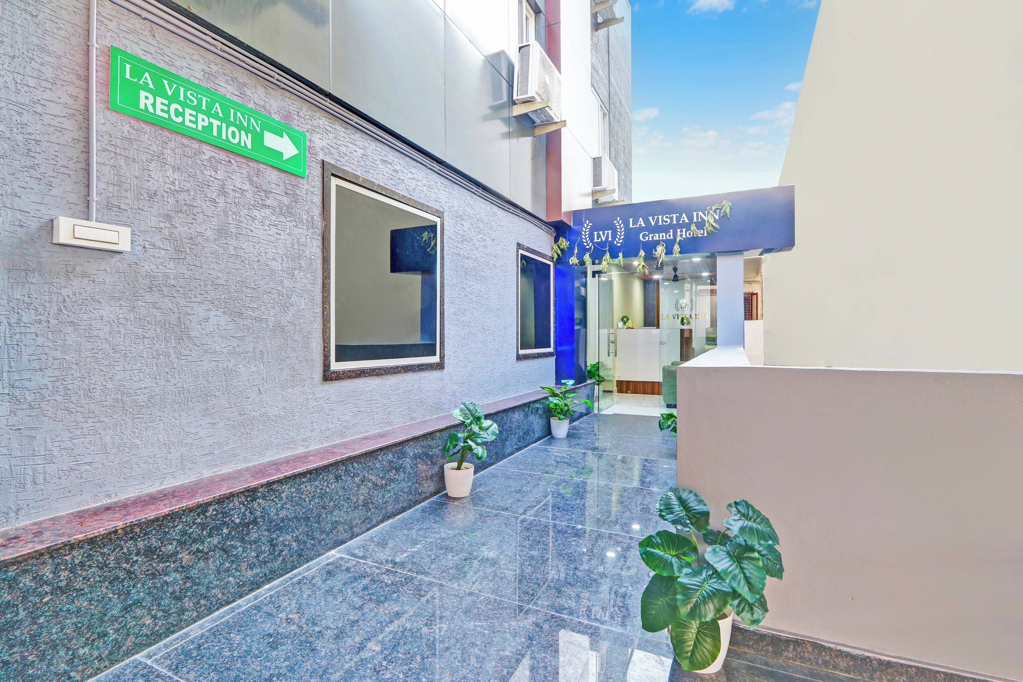 Un espace d'accueil d'hôtel comprenant un comptoir de réception, un panneau indiquant la réception et une entrée bleue menant à l'hôtel.
