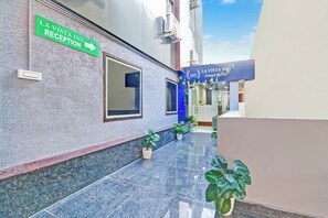 A hotel reception area with a reception desk, a sign for the reception, and a blue entrance to the hotel.