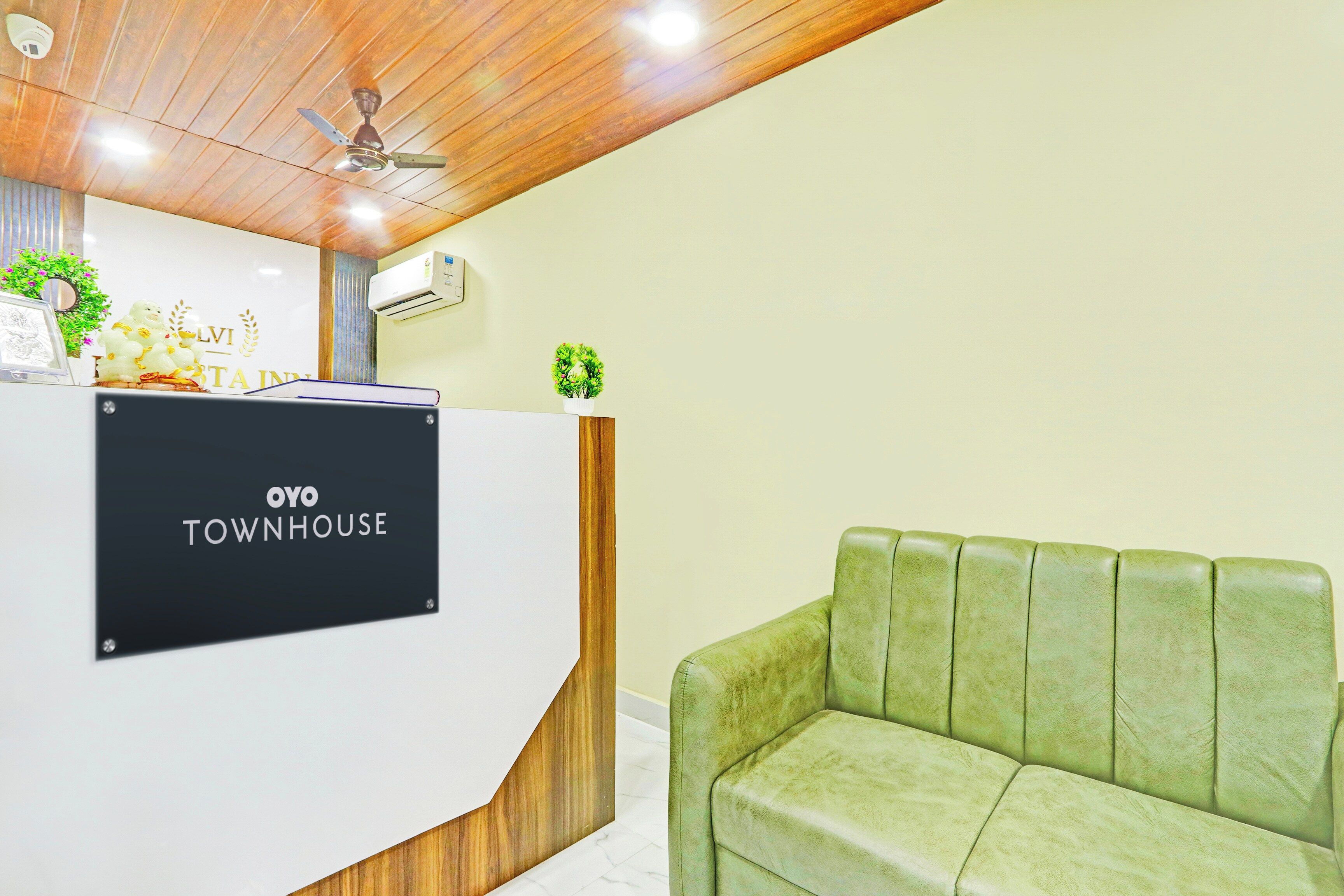 A reception desk with a sign reading 'OYO TOWNHOUSE' and a green upholstered sofa.