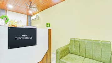 A reception desk with a sign reading 'OYO TOWNHOUSE' and a green upholstered sofa.