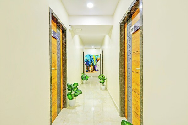 A hotel corridor with wooden doors, a marble floor, and a colorful elephant mural on the wall.