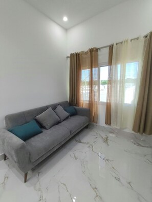 A living room with a grey sofa, two cushions, and a marble floor. - Twin Paradise Villas I (Hato Nuevo)