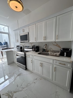 A modern kitchen with white cabinetry, a built-in oven, a microwave, and a stainless steel sink. - Twin Paradise Villas I (Hato Nuevo)