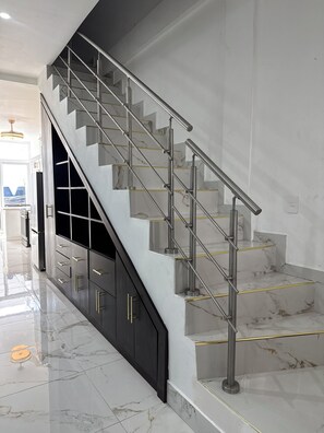 A modern staircase with a glass railing, marble steps, and black cabinets. - Twin Paradise Villas I (Hato Nuevo)
