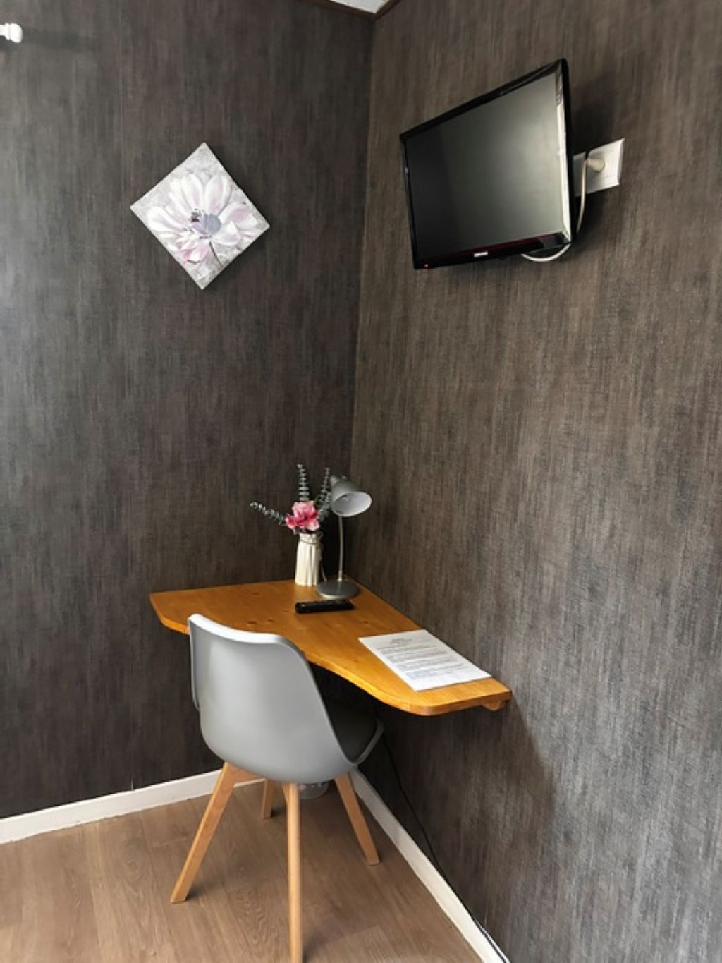 A corner room with a desk, chair, and a mounted TV.