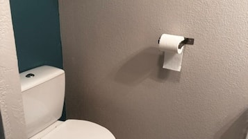 Un baño pequeño con inodoro, dispensador de toallas y soporte para papel higiénico en la pared.