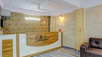 A reception area with a wooden reception desk, a framed picture on the wall, and a brown leather chair.