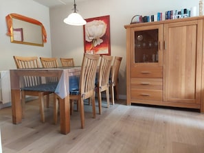 A dining area with a wooden table and chairs, a cabinet with glass doors, and a painting on the wall. - Sleedoornstraat 15 (Cadzand-Bad)