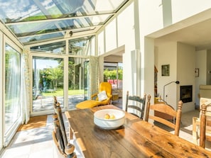 A dining area with a wooden table, chairs, and a glass enclosure. - Holiday Home With 3 Bedrooms (Burgh-Haamstede)