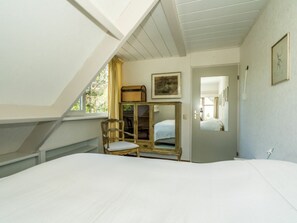 A bedroom with a bed, a chair, a wardrobe, and a mirror. - Holiday Home With 3 Bedrooms (Burgh-Haamstede)