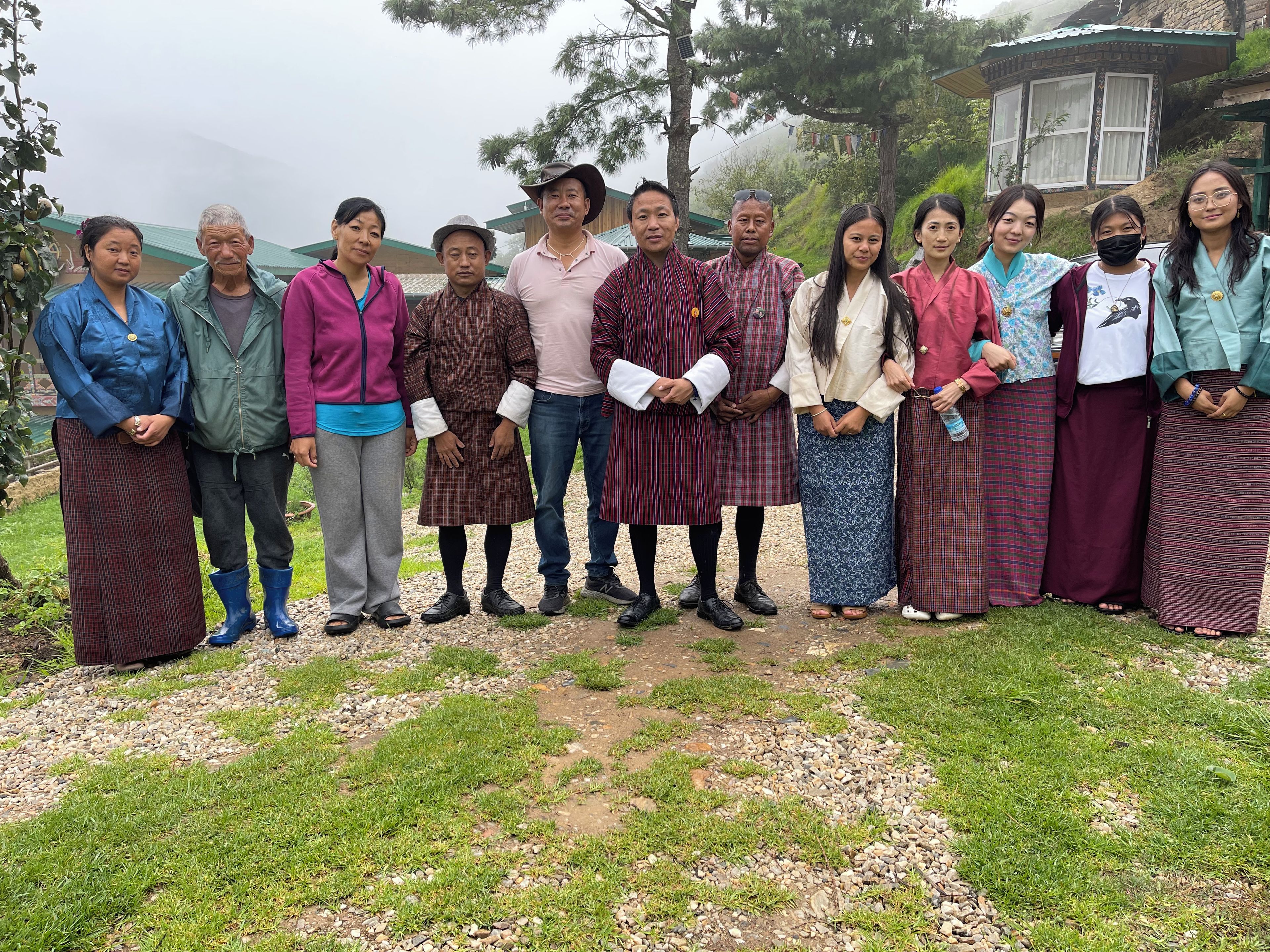 A group of people standing in a garden with a building in the background.
