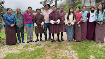 A group of people standing in a garden with a building in the background.