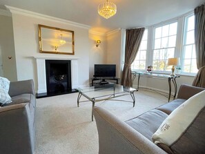 A living room with a fireplace, television, and seating area. - 2 bedroom accommodation in Whitby (Whitby)