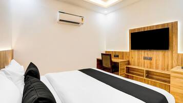 Habitación de hotel con cama, escritorio, silla, televisión de pantalla plana montada en la pared y equipo de aire acondicionado.