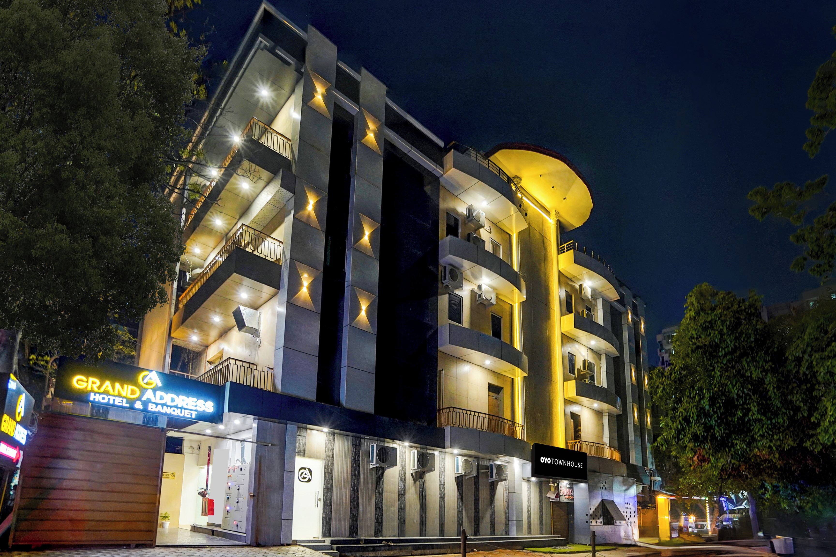 Ein modernes Hotel mit mehreren Balkonen, einer Rezeption und einem Schild mit der Aufschrift 'Grand Address Hotel & Banquet'.